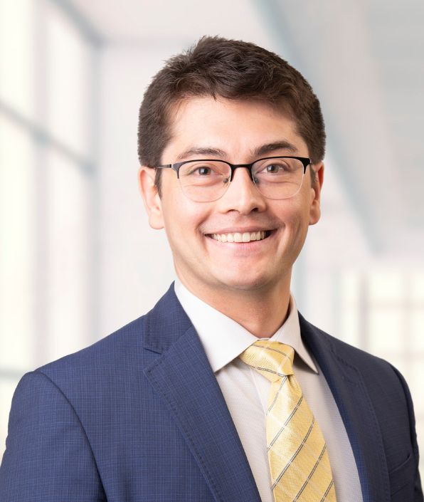 man with brown short hair, glasses, yellow tie and blue suit coat