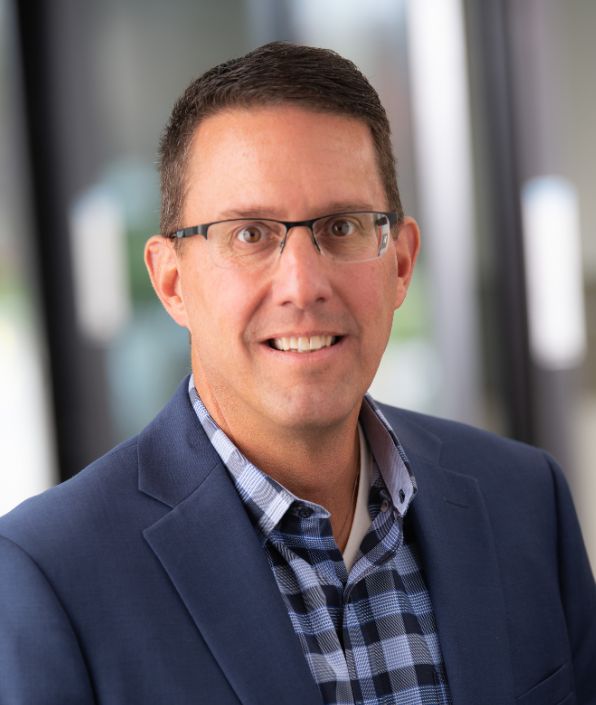 man with short brown hair and glasses in a blue plaid shirt