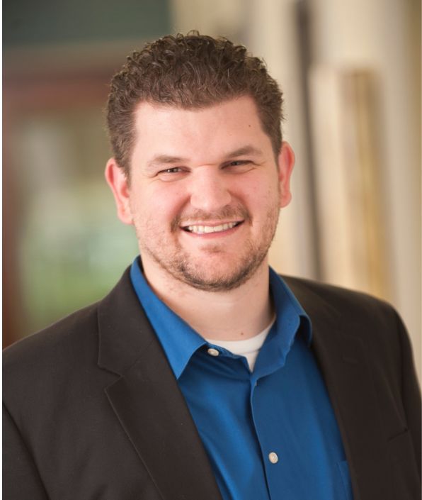 main with beard and short light brown hair in suit coat