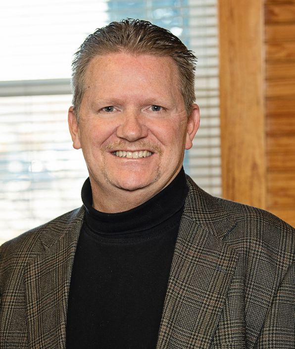 man in tan suit jacket with short light brown hair