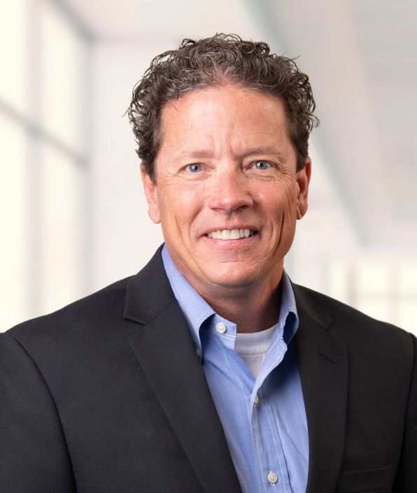 brown curly haired man in navy suit coat