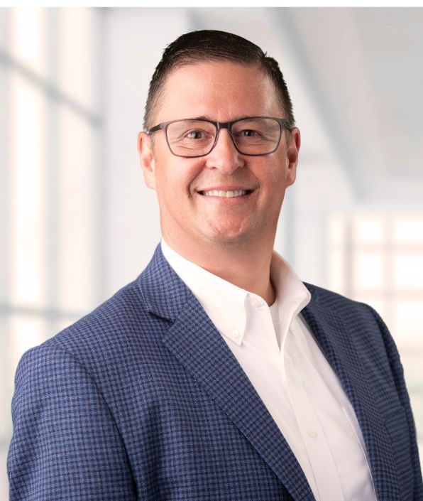 man with short hair and glasses in a blue suit with white shirt