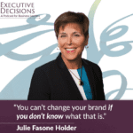 A woman with short brown hair, wearing a dark blazer over a blue top and a necklace, smiles at the camera. The background features a light abstract design. Text on the image reads: "Executive Decisions: A Podcast for Business Leaders" and "Julie Fasone Holder: 'You can't change your brand if you don’t know what that is.'" This podcast offers insights from influential corporate women.