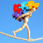 A wooden mannequin balances on a tightrope, skillfully engaging in risk planning as it carries colorful puzzle pieces labeled with the letters "R", "I", "S", and "K" above its head. The sky in the background is clear and blue.