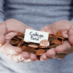 A pair of hands holding a pile of pennies with a small card on top that reads "College Fund." The background is out of focus, emphasizing the hands and the card.