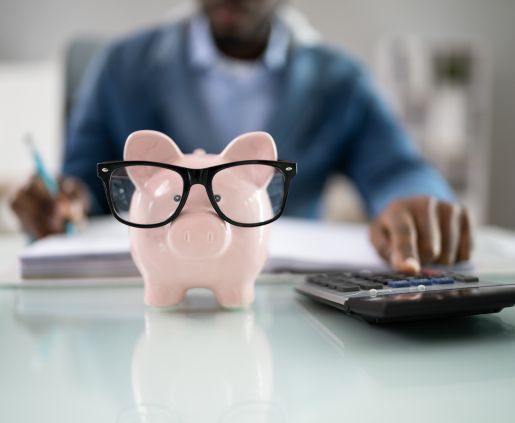 piggy bank with glasses on a desk by a computer